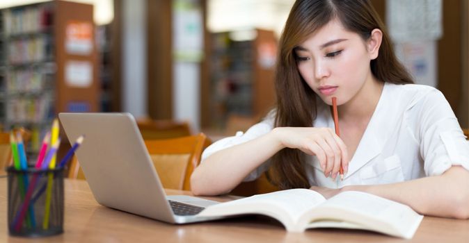 asian-student-reading-textbook-and-working-on-computer-in-deep-thought