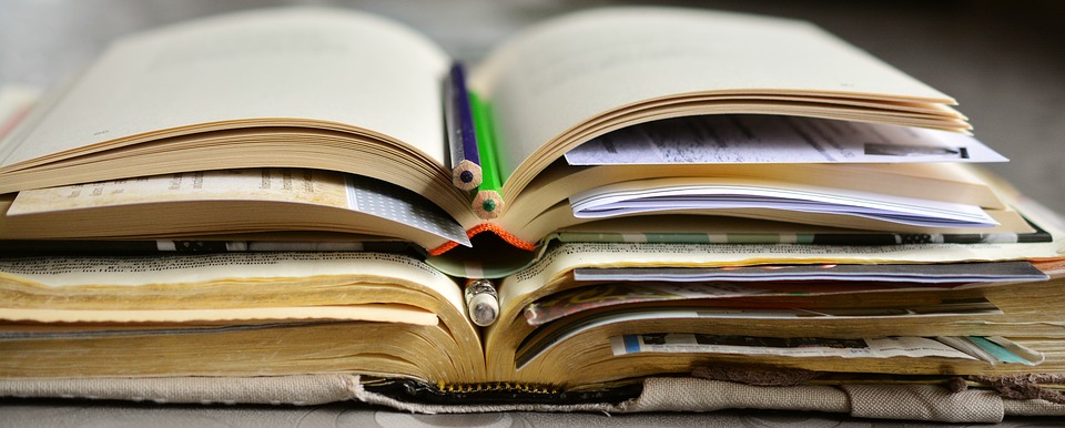 three-books-open-with-bookmarks-and-pencils-in-between-while-stacked-on-top-of-one-another