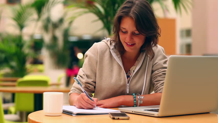 student-learning-online-while-writing-notes-outdoors-with-laptop-and-coffee-or-tea