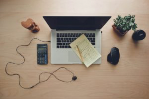 computer-on-table-next-to-scientific-calculator-and-potted-plant-with-notebook-on-top-of-keypad-with-mouse